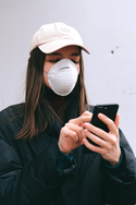 Woman wearing mask while video chatting on phone, illustrating using Zoom videoconferencing during the COVID-19 coronavirus pandemic